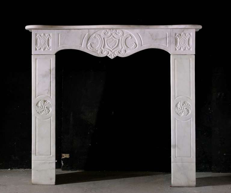 19th century Italian Carrara marble mantel with Heraldic carved centrepiece and capital blocks. Opening dimensions: 31.25