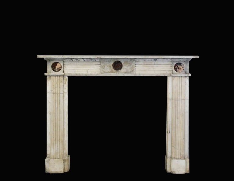 A Mantle of handsome proportions carved in carrara marble, with fluted jambs, and frieze terminating at corner blocks, and center tablet with red inlay medallions.