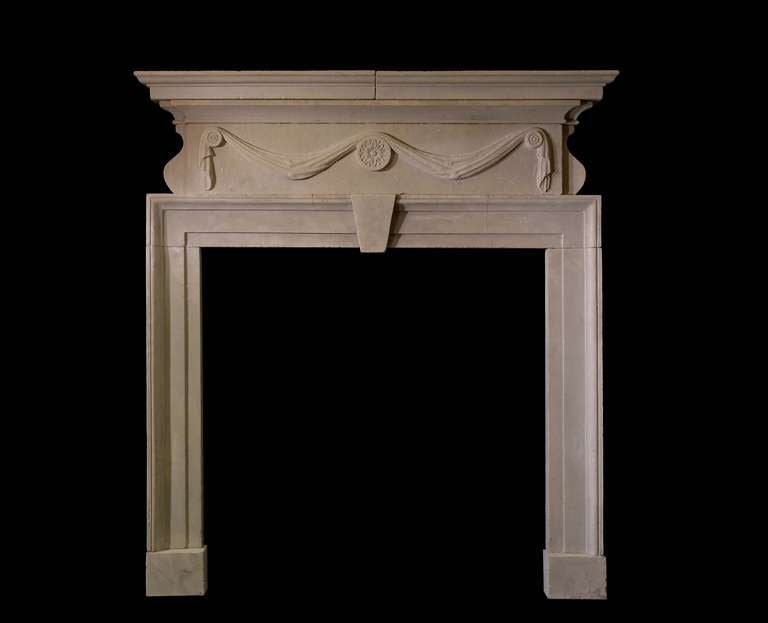 Georgian mantel in bathstone with drapery swagged medallions to the frieze and side facing corbels. Architrave moulding framing the aperture with central key stone. Corniced shelf. Opening dimensions: 39.5