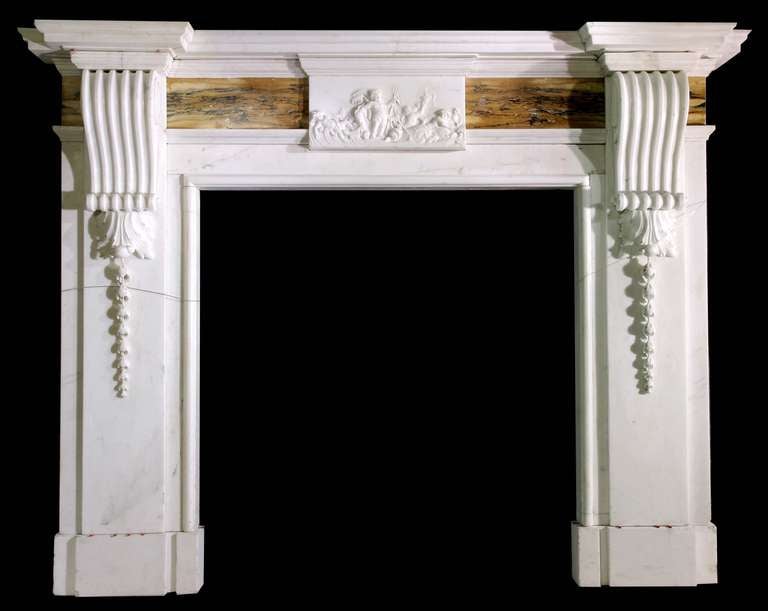 An English mantel in Statuary marble with bookmatched Siena frieze panels each side of a carved center tablet with strong corbels under the corniced shelf. Opening dimensions: 42