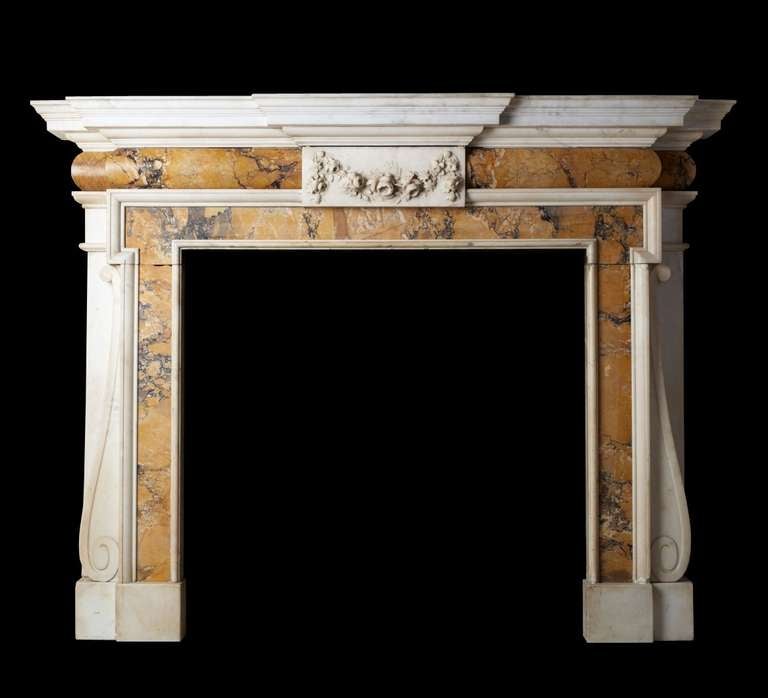 Palladian style chimney-piece carved in statuary and Siena marble with floral center tablet and stepped shelf barrel frieze and invert console jambs. Opening dimensions: 40.25" W x 38.75" H.
