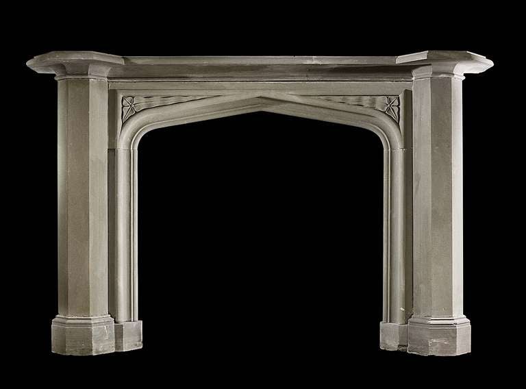 A grit stone mantel from the Regency period in the Gothic manner with carved spandrels and plain columns on block feet. Opening dimensions: 40.75