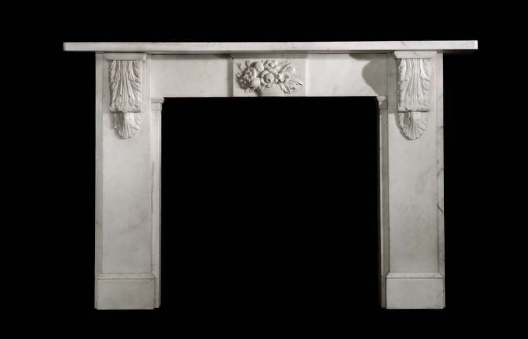 An early Victorian circa 1840-1860 Italian statuary marble mantel with carved acanthus leaf corbels and a carved centre tablet with a basket over flowing with fruit and flowers. Opening dimensions: 38.5