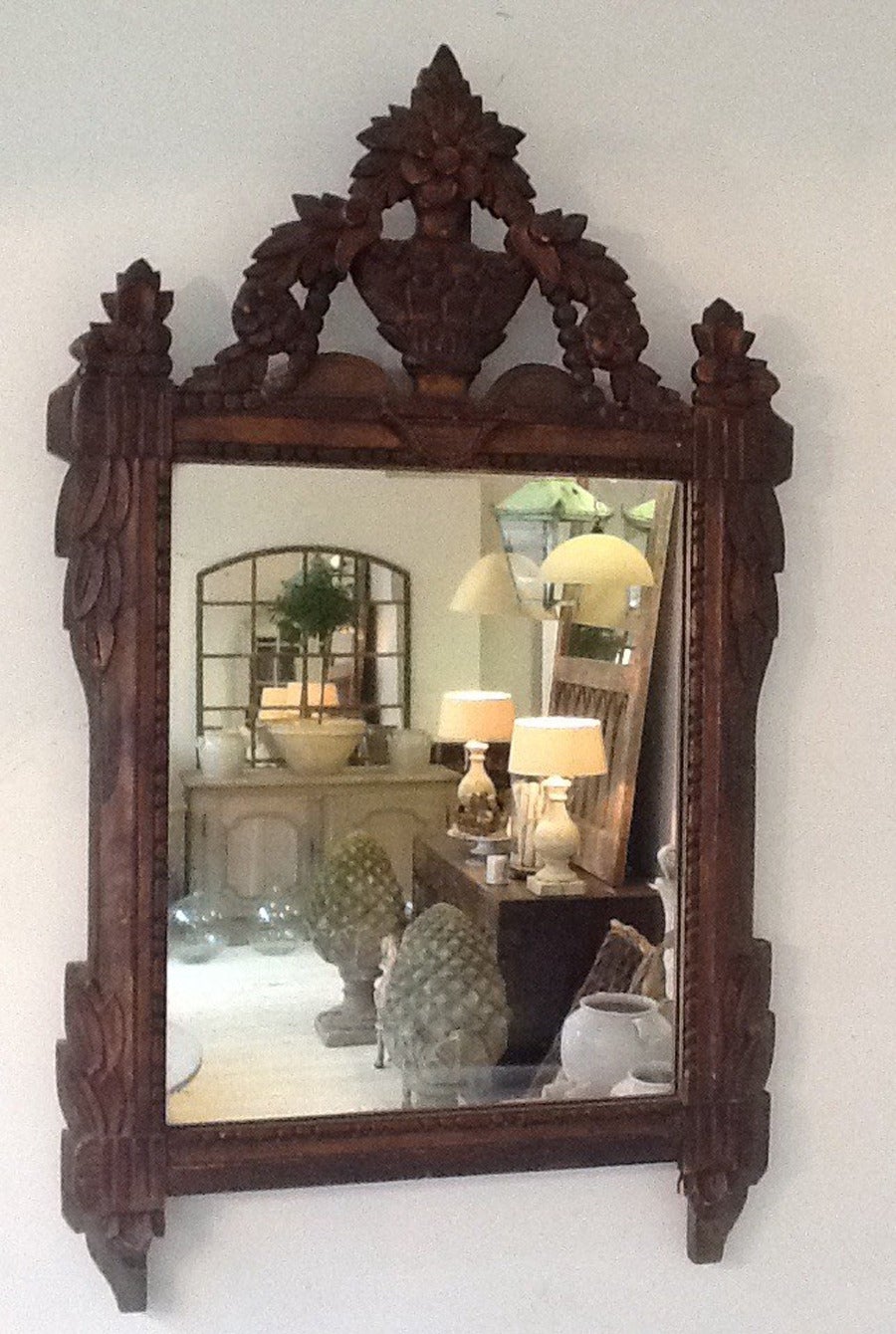 A very handsome 19th century French mirror with gilt wood carving on a wooden frame. The mirror is crested with an urn and foliate and the top carved layer is gilded and highlighted with a red clay pigment that is now exposed as the leafing has worn
