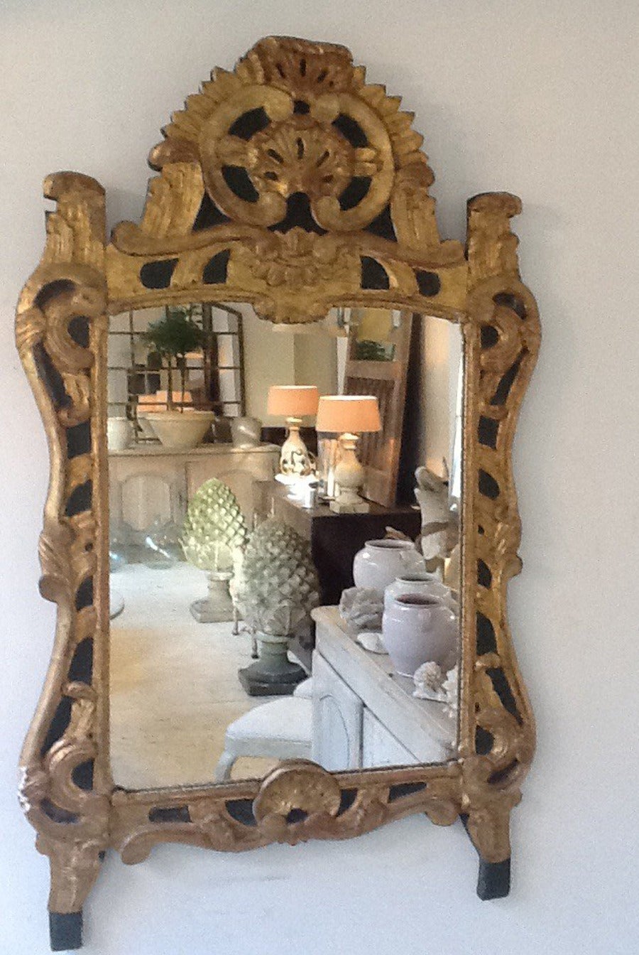 This is a stunning 19th century French Regence-style giltwood carved mirror with original mirror plate.  This mirror features a shell and foliate design with a very dark olive green painted background. We love this mirror’s aged gilt patina and