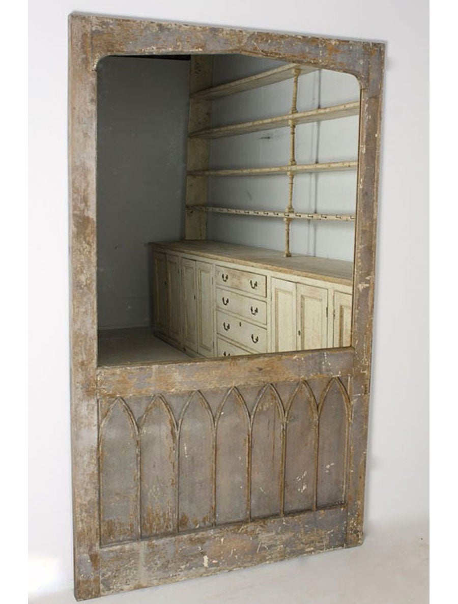A very large and decorative 19th century original painted, pine Gothic traceried door converted into a mirror.  This stunning mirror has traces of several layers of distressed gray, brown, and white paint with later lightly distressed mirror plate. 