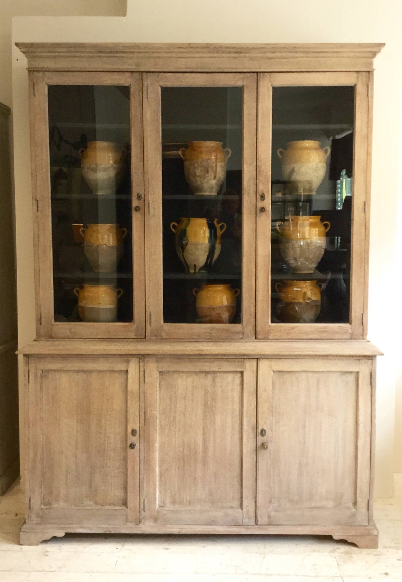 A handsome bleached oak English vitrine in two parts from the 19th century with original glaze (glass) and adjustable shelves. The upper section interior is painted in a charcoal paint.
