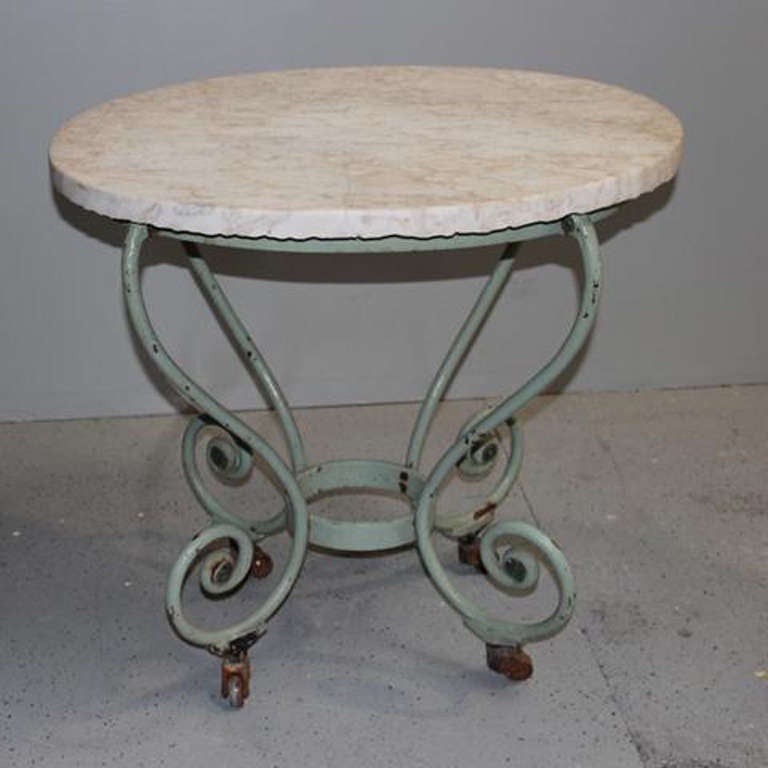 19th century French butcher table with original marble top, wrought iron base, and caster wheels. The company loves this piece for its highly unusual oval shape and beautifully fresh turquoise patina. This French butcher table was found in