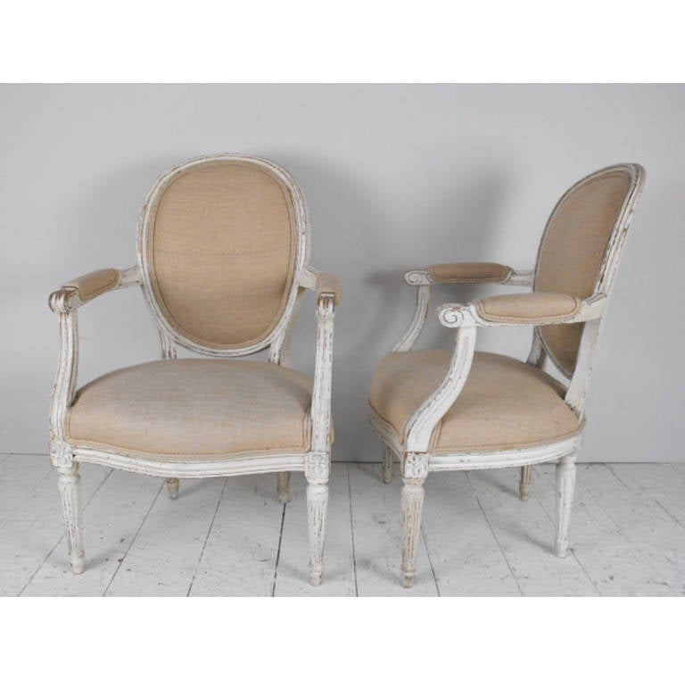 An excellent pair of French fauteuils with original paint in the Louis XVI style.  These chairs were recently reupholstered in a lovely antique hemp linen.  Circa 1920.