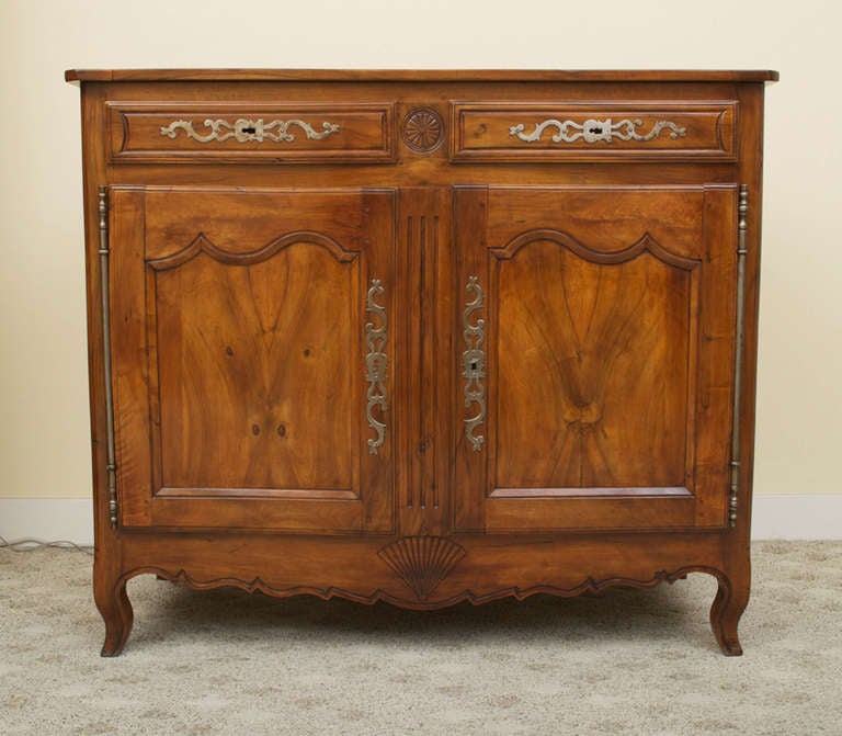 A stunning Louis XV solid French walnut buffet. The two dovetailed drawers are above two raised and recessed paneled cabinet doors with a carved scalloped apron below. This buffet retains its beautiful, rich, original color and patina and has a