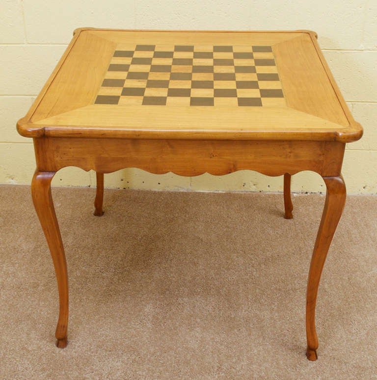 A gorgeous, Louis XV style cherrywood game table with removable flip-top. One side of the table top has a lovely cherrywood and ebonized game board and the other side has an embossed, rich green leather top. The scalloped apron leads to four