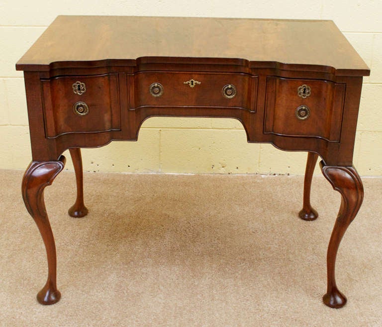 A beautiful flame mahogany Queen Anne style lowboy. The center drawer is flanked by two smaller and deeper drawers. This piece is raised on carved cabriole legs ending on pad feet. The lowboy has a gorgeous, rich color and a fresh French polish.