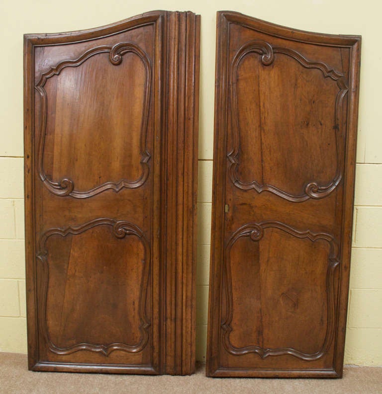 A gorgeous pair of carved Louis XV solid French walnut armoire doors. Both doors have two raised and recessed panels. These doors retain their beautiful, rich, original color and patina and have recently been waxed.
 
 The left door is 31.5