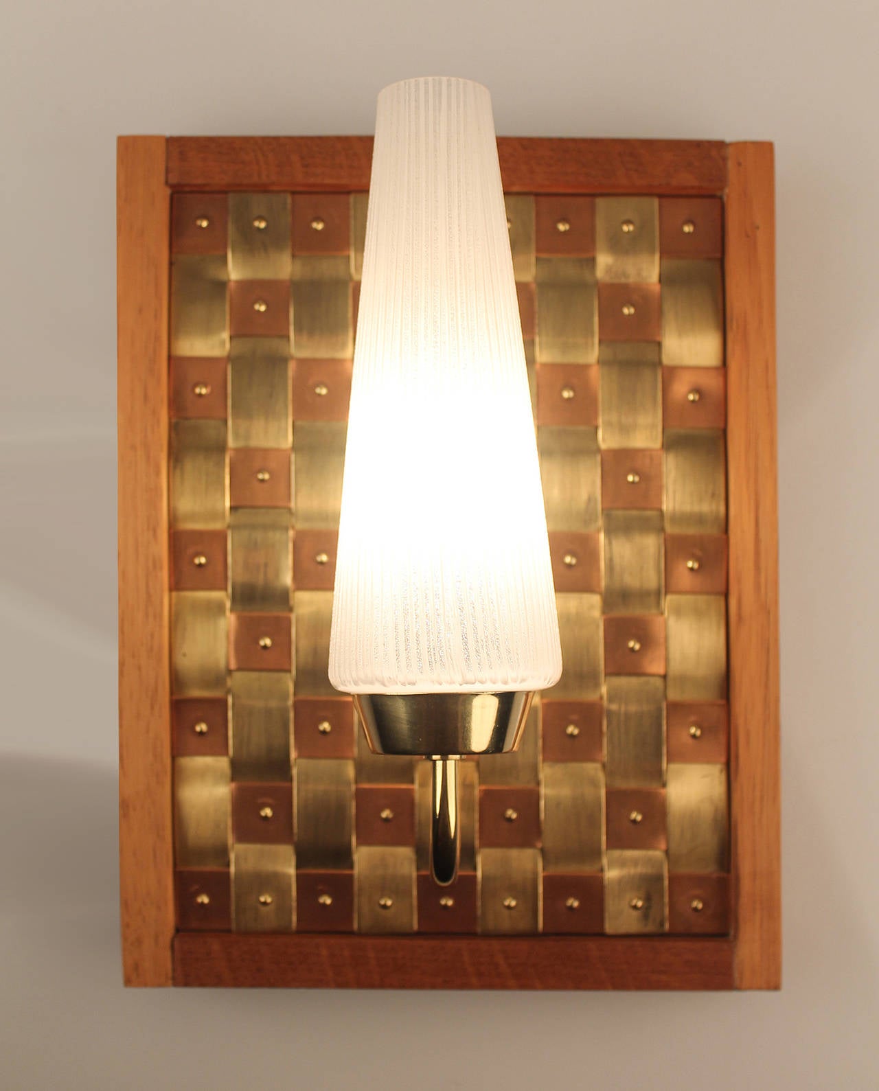 Complimentary Express Shipping included in price

Pair of one-off mid century sconces, with a stunning weaved copper and brass
wickerwork enshrined in wooden frame,  light with conical glass shade mounted on a brass stem, probably