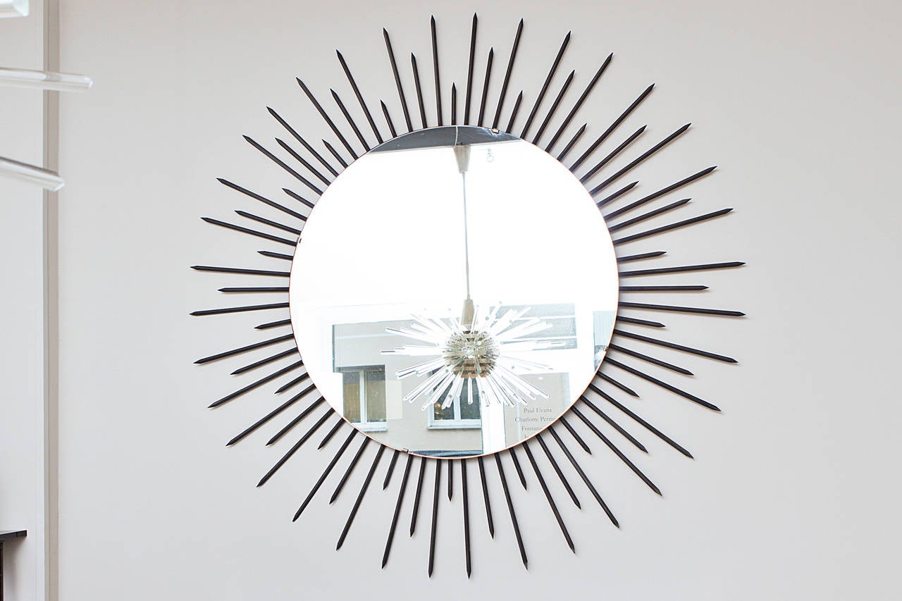 Outstanding large sunburst mirror, France, circa 1955. Iron sunburst frame, wooden suspension, mirror glass. Measures: Diameter 180 cm, depth 5 cm, diameter mirror 110 cm.