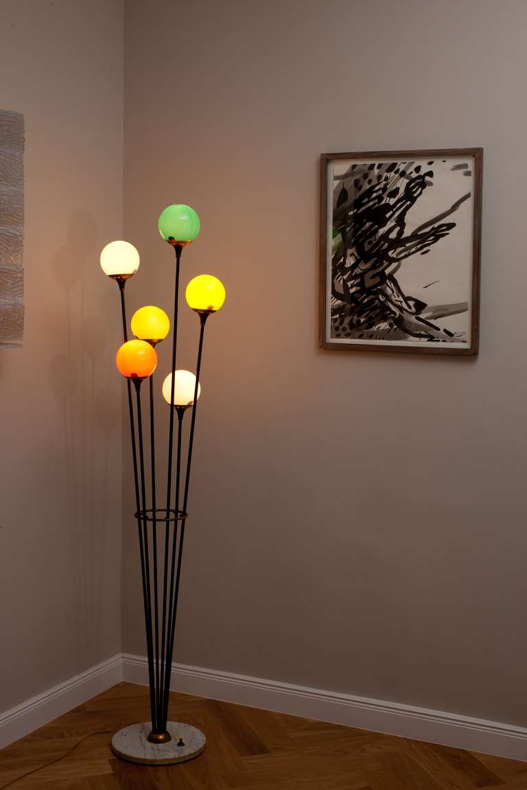 Attr. Stilnovo floor lamp, Italy circa 1950, black lacquered metal, brass fittings, marble base, six lights with five different colloured glass ball shades, height 171 cm, marble base diameter 30 cm, diameter each glass ball 12 cm, three step switch
