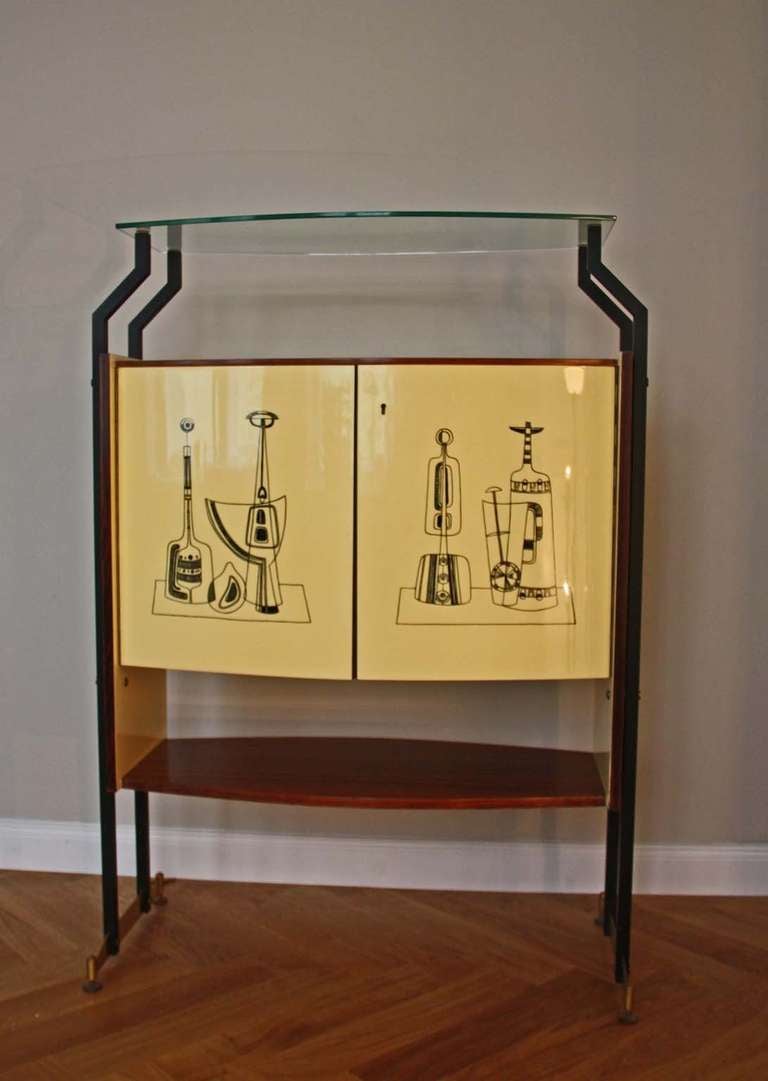 Bar Cabinet, Italy circa 1950, very nice decorations, two doors, glass plate inside, decorated on two sides. Black laquered metal legs, mahogany veneered, painted doors, brass legs, brass key.