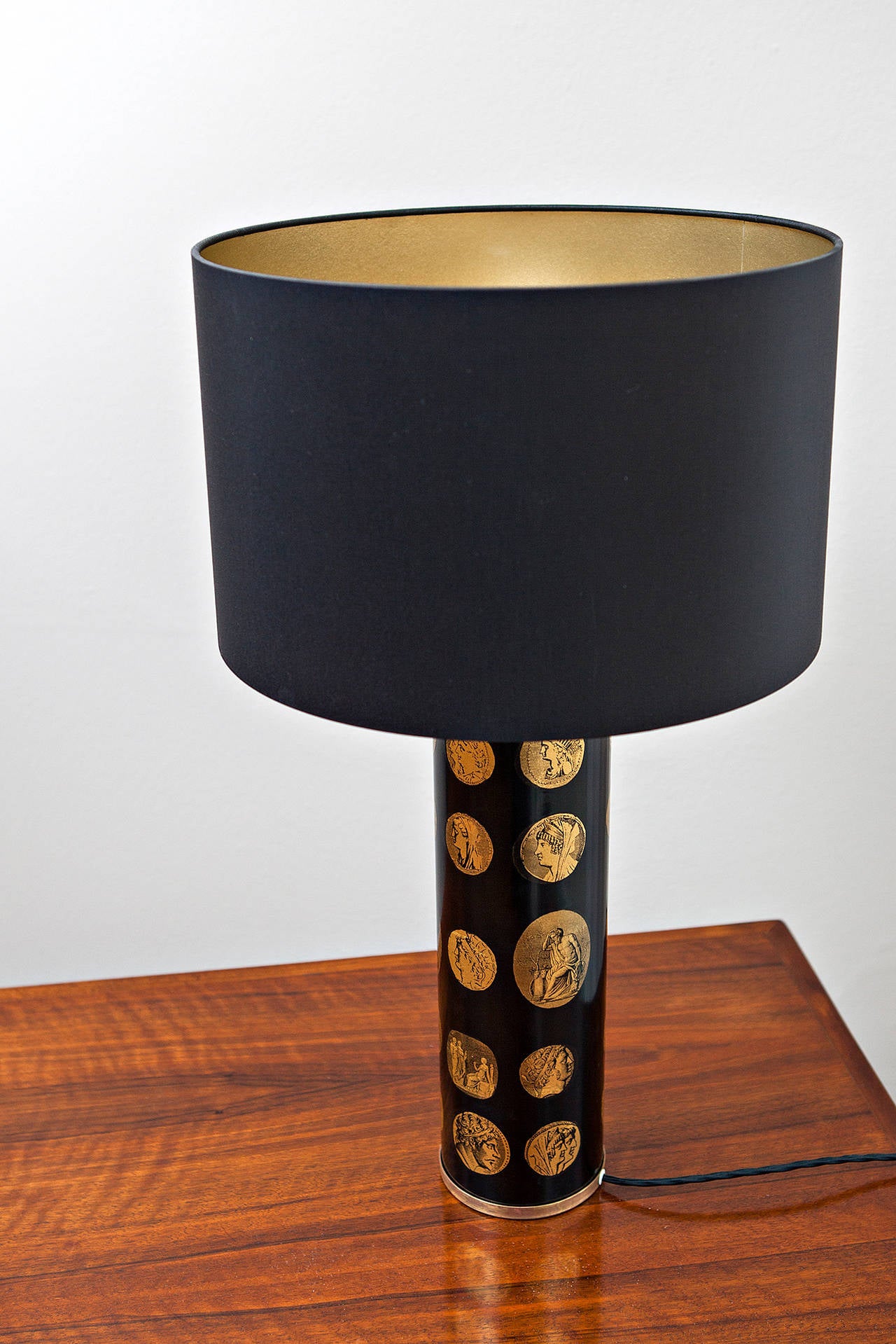 Piero Fornasetti (1913-1988), enameled table lamp in black with gold transfer printed lithographic cameos of emperors with brass details, signed with label on the base.
New black silk shade with inside gold: diameter 33 cm, lamp with shade is 58 cm