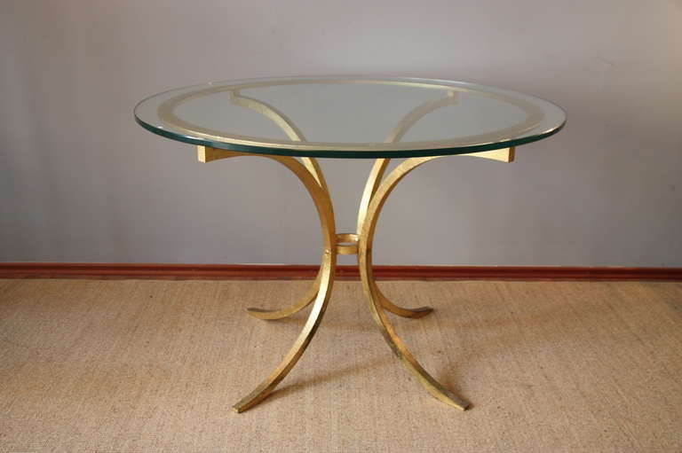 circular table / dining table, sidetable by France Designer Roger Thibier, France circa 1960, gilt patinated iron base with a circle on four arched feet joined with a ring, heavy glass top.