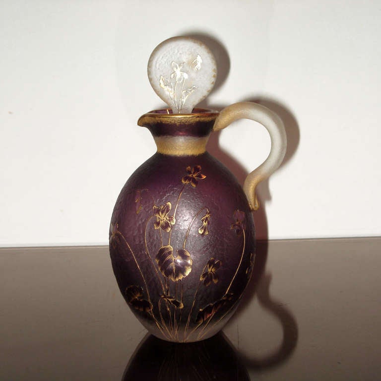 A wonderful and very rare cristallerie Daum Nancy, rounded pitcher with applied handle, beautiful etched surface and gilt violets decor. Double face stopper with two violets on one side and one violet on the other.
Signed «Daum Nancy» with Cross of
