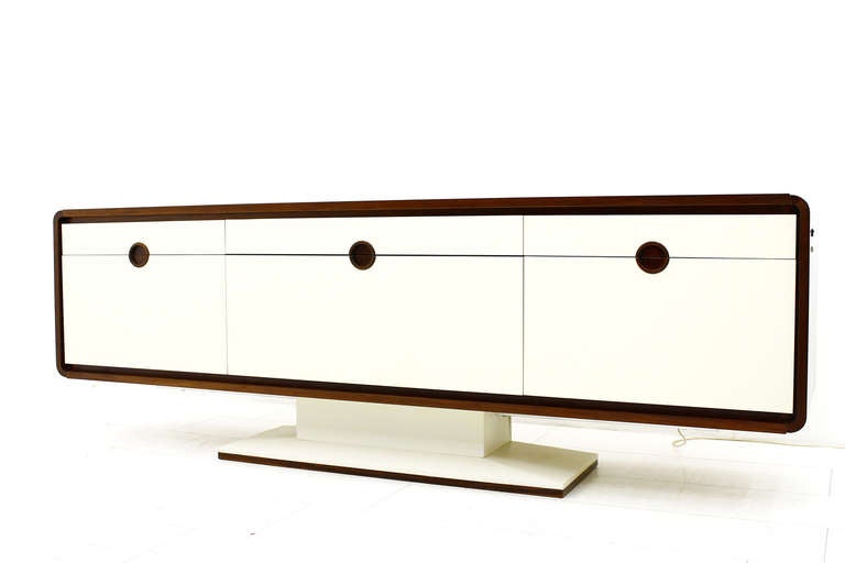 A Special Sideboard with an electric Bar and Mirror from the 70`s probably Germany. 
By pressing a button moves up from the rear part a illuminated mirror Bar.
The sides and the surface is veneered with rosewood. The Front and the Foot are coated