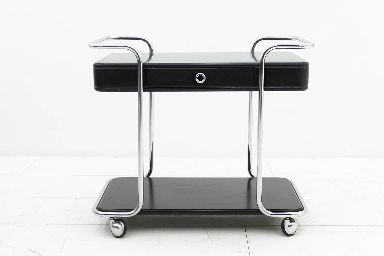 Black lacquered bar trolley with one drawer. Steel tube and four wheels.

Good original condition with sign of age.