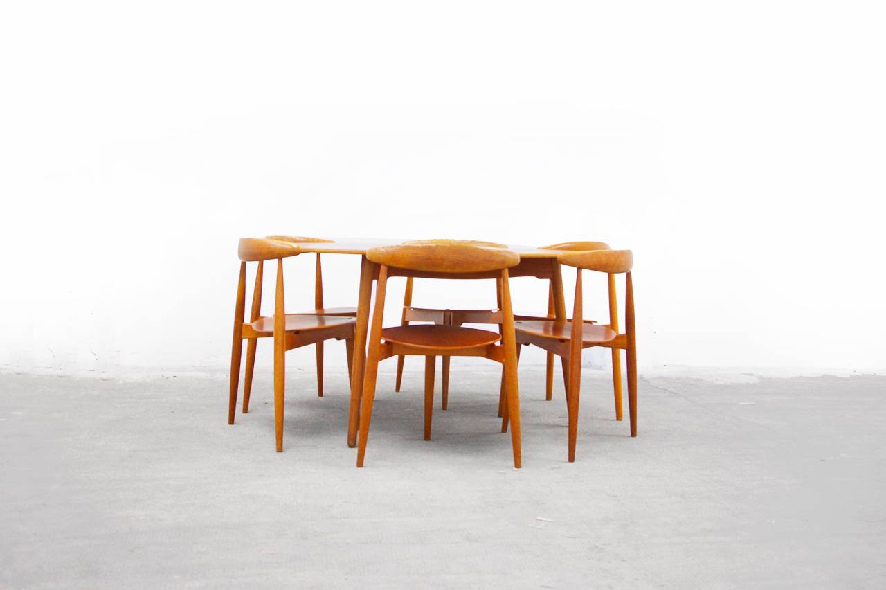 This six person dining table set  designed for Fritz Hansen by Hans Wegner is rare find. Created of both teak and oak wood, the unique design perfectly encapsulates all three-legged chairs under the round table top. The entire group in is great