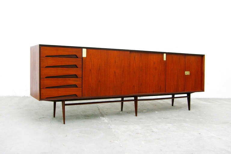 A teak credenza by Edmoudo Palutari for Dassi, Italy.
This charming piece is very well crafted and is highlighted by the gorgeaous material selection,
unique brass hardware and nice warm teakwood.
Behind the doors, there is plenty of room for