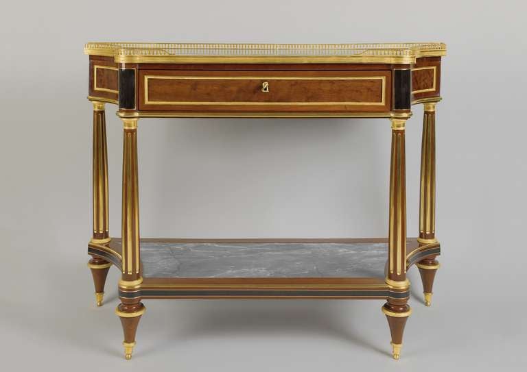 Elegant Console Desserte in rectangular shape with inward sloping sides. The blue-grey and white marble top with three-quarter ormolu gallery above a central frieze drawer. On fluted - partly gilt - column legs. Various metal and ormolu bronze