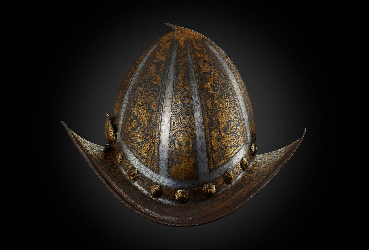 This morion helmet is elegantly forged from one single plate of iron, rising to a back turned stalk at its apex and showing a file-roped down turned edge at each side, seperated from the brim by a recessed chamfer. Towards the front and back end the