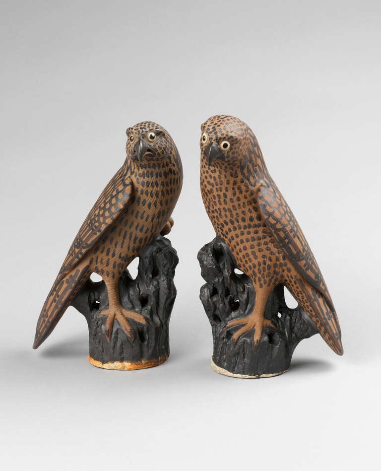 This well modelled pair of Chinese export stoneware hawks are painted realistically in brown with speckled feathers. The head slightly turned to the side in alert pose, one foot standing on a pierced rockwork base, the other tucked into the breast.