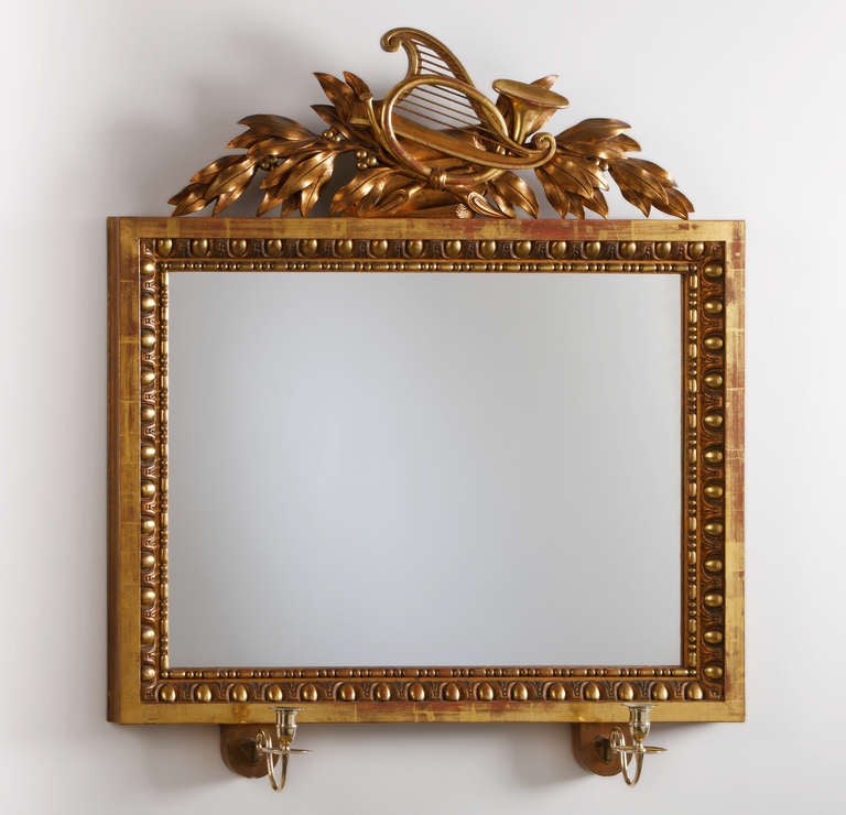 La plaque rectangulaire est surmontée d'un trophée musical cerné de feuilles d'accanthe. Deux branches en laiton à volutes. Le miroir est signé par le fabricant Petter Gustaf Bylander, Göteborg (1811-1852) avec une étiquette en papier au dos.