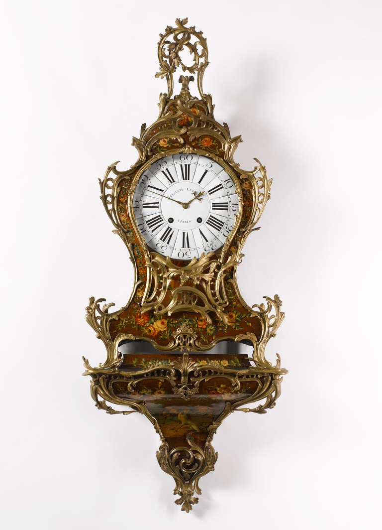 The clock case decorated overall with very fine ‘Vernis Martin’ lacquer paint with floral sprays and garlands. The waisted case with pierced foliate bronze mounts and surmounted by a foliate finial with a bird. On scroll feet, the bracked