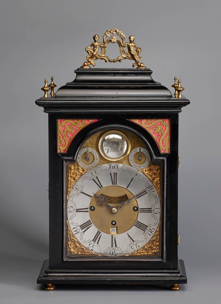 An attractive Austrian mid-18th century Baroque period quarter-striking bracket clock by the maker Andreas Hohenadl (1714-1793), Vienna. The ebonised fruitwood case with figurative brass carrying handle to the inverted bell top, arched glazed