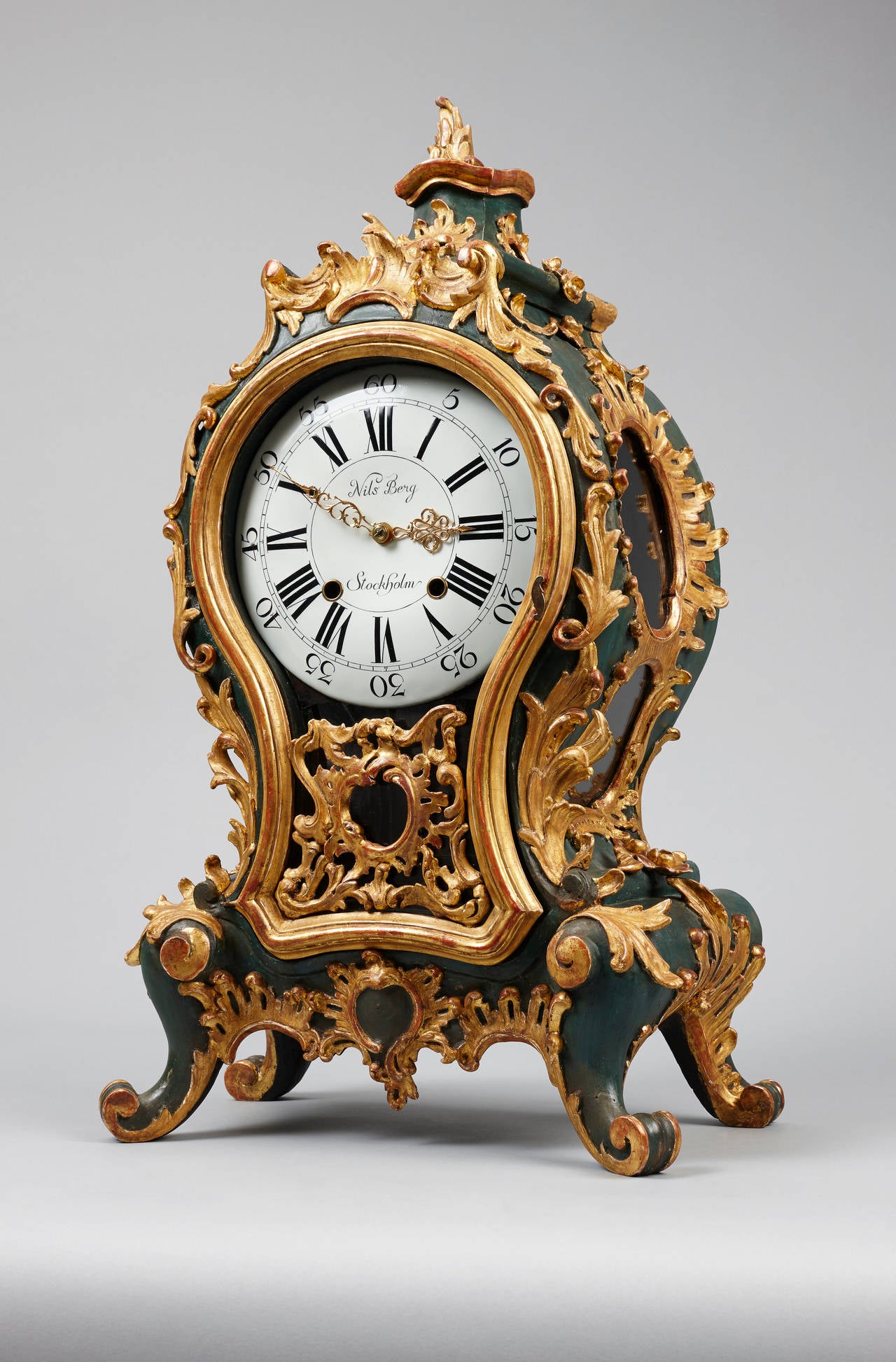 The large Rococo ornate case made of solid wood, boldly carved with scrolls, painted in dark green and partially gilded. The Roman and Arabic white enamel dial signed in the centre: Nils Berg Stockholm (1721-1794). Finely chiseled gilt brass hands.