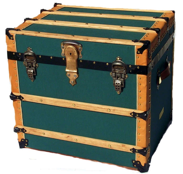 Square shaped and recovered in green canvas duck, this trunk has all of its original cast hardware, complete with its' original solid brass working Eagle lock with key and over-sized cast draw bolts.  Slats are butter-smooth natural oak and binding