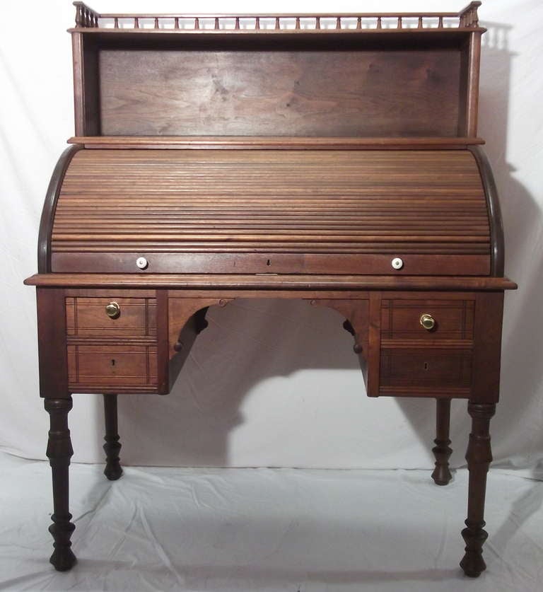 Eastlake era tambour cylinder roll top walnut desk.  4 turned legs, pair of drawers each side.  Plain writing surface.  Decoration of shallowly incised line.