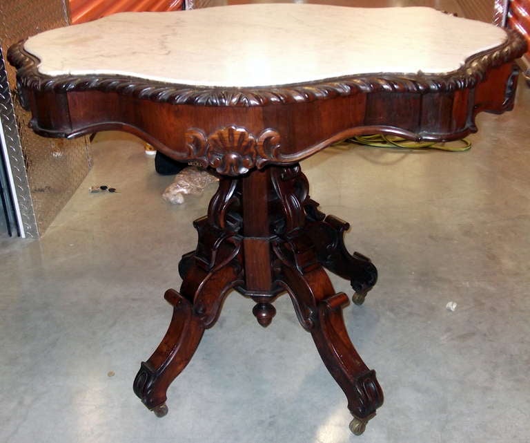 Rosewood and marble turtle top table.  Four splayed legs with c- and s-scrolls sitting on casters.  Marble inset top is decorated with  carved shell motifs and shallow gadrooning.