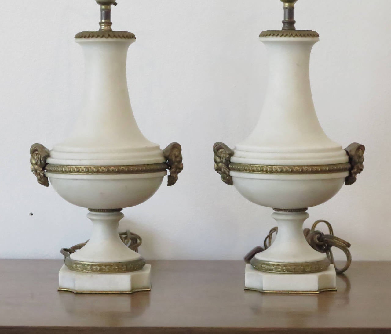 Lovely pair of neoclassical table lamps crafted in solid alabaster with elegant gilt detailing and grecian figureheads.