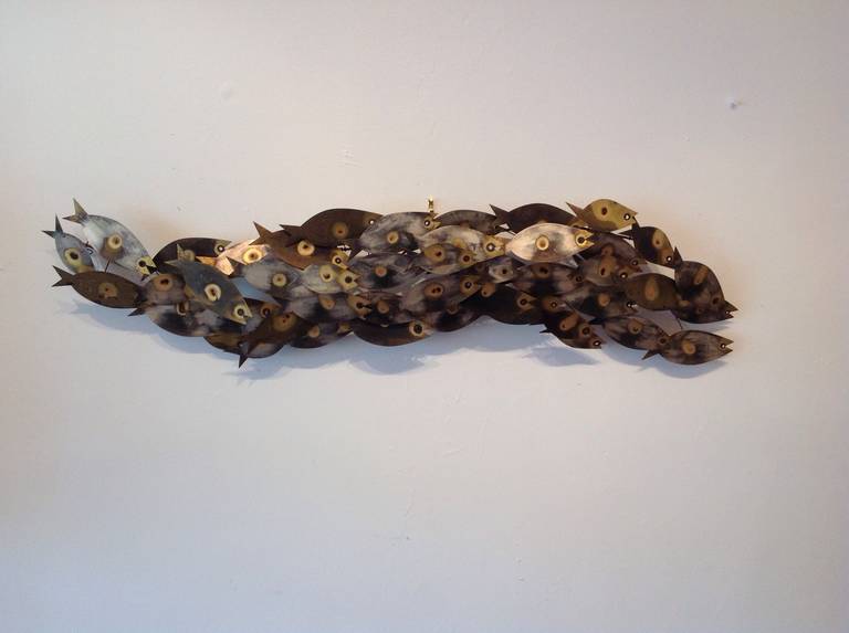 Beautifully designed streamlined modernist wall sculpture of a swimming school of fish by Curtis Jere. Crafted from brass with torched eyes and markings. Signed and dated 1969.