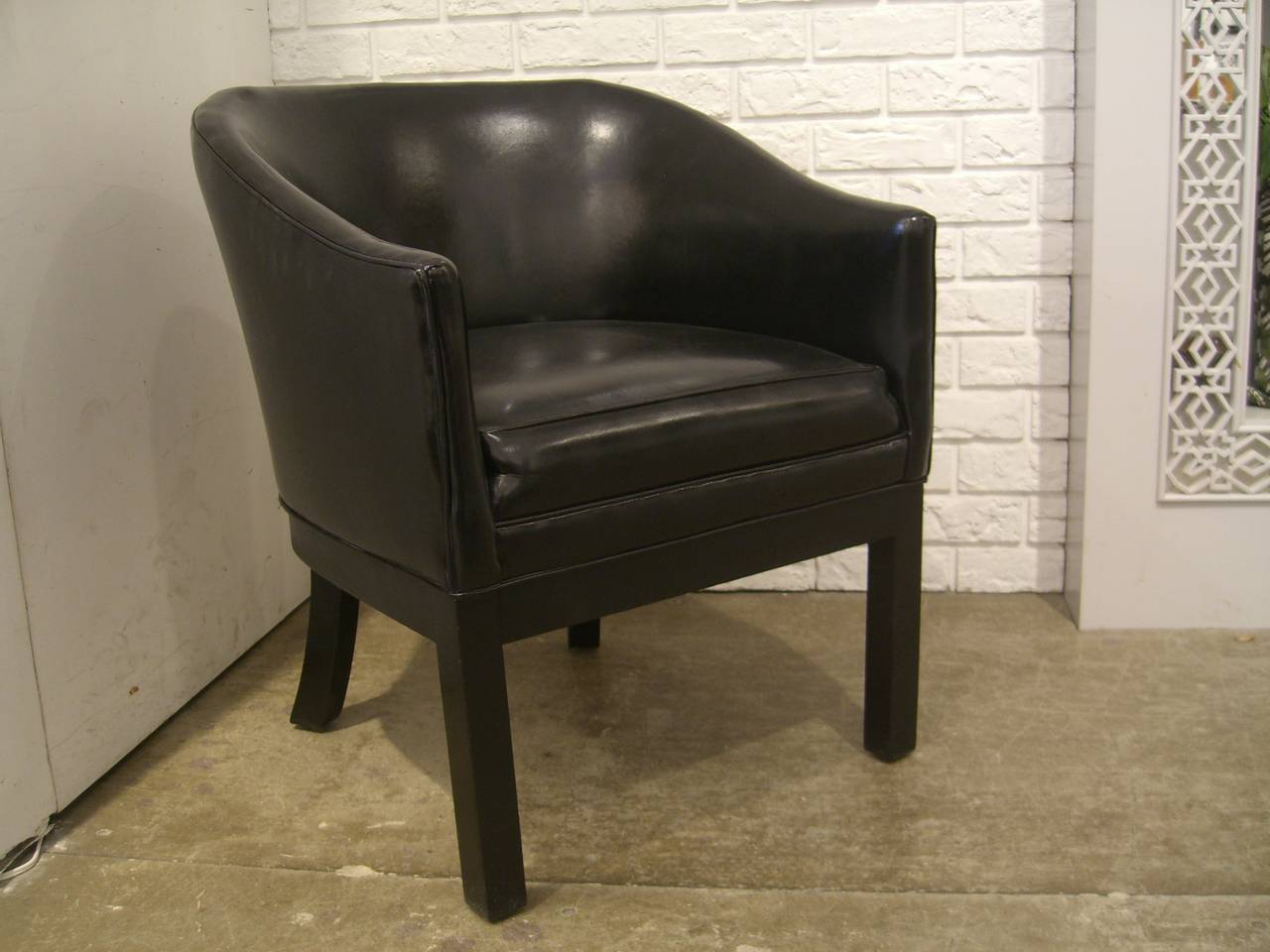 Black vinyl occasional chair with black legs.