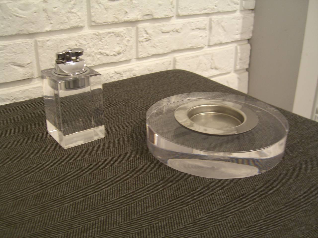 Lucite smoking set containing an ashtray with stainless steel insert and lighter. Lighter does work with fluid. Lighter is 4.5 H x 2.25 W.
