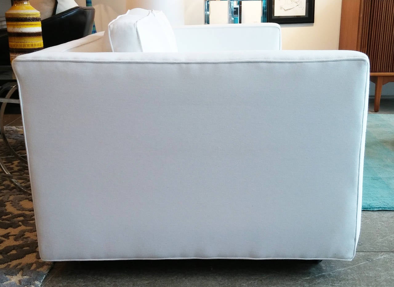 Fantastic white upholstered low back loveseat on casters.