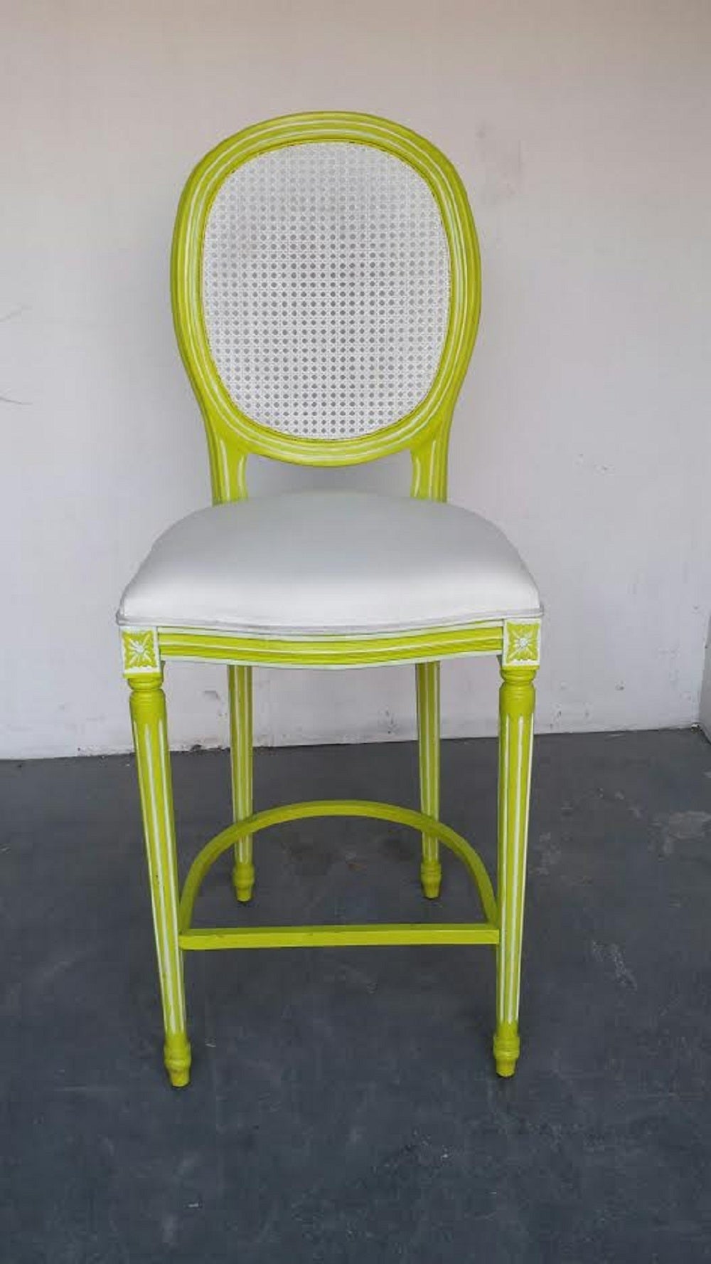 A pair of bar stools in the French Louis XV Provincial style. Finished in distressed lime green. Seat upholstered in white faux leather.