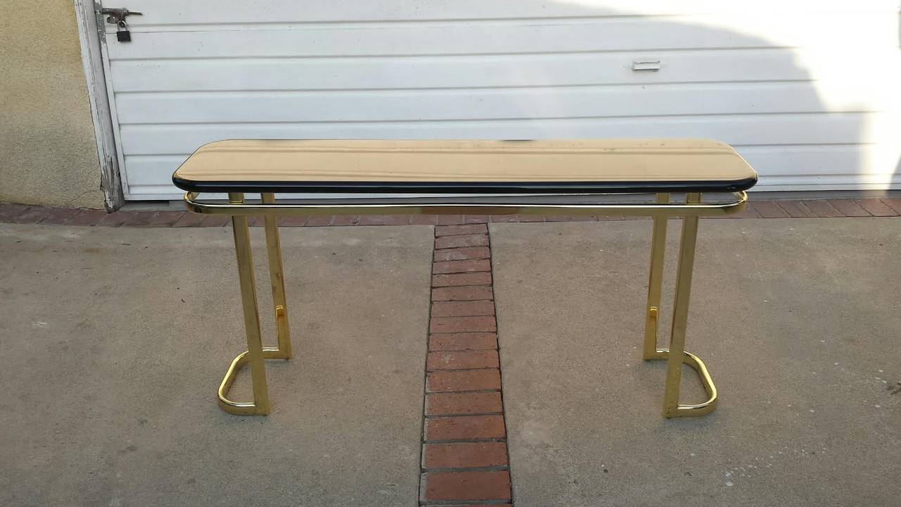 Mid Century Modern Console Table in Mastercraft Style. Black lacquered oblong wooden top sits on a brass frame.