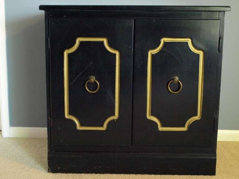 Two door black and gold chest with brass hardware.
Inside one shelf.