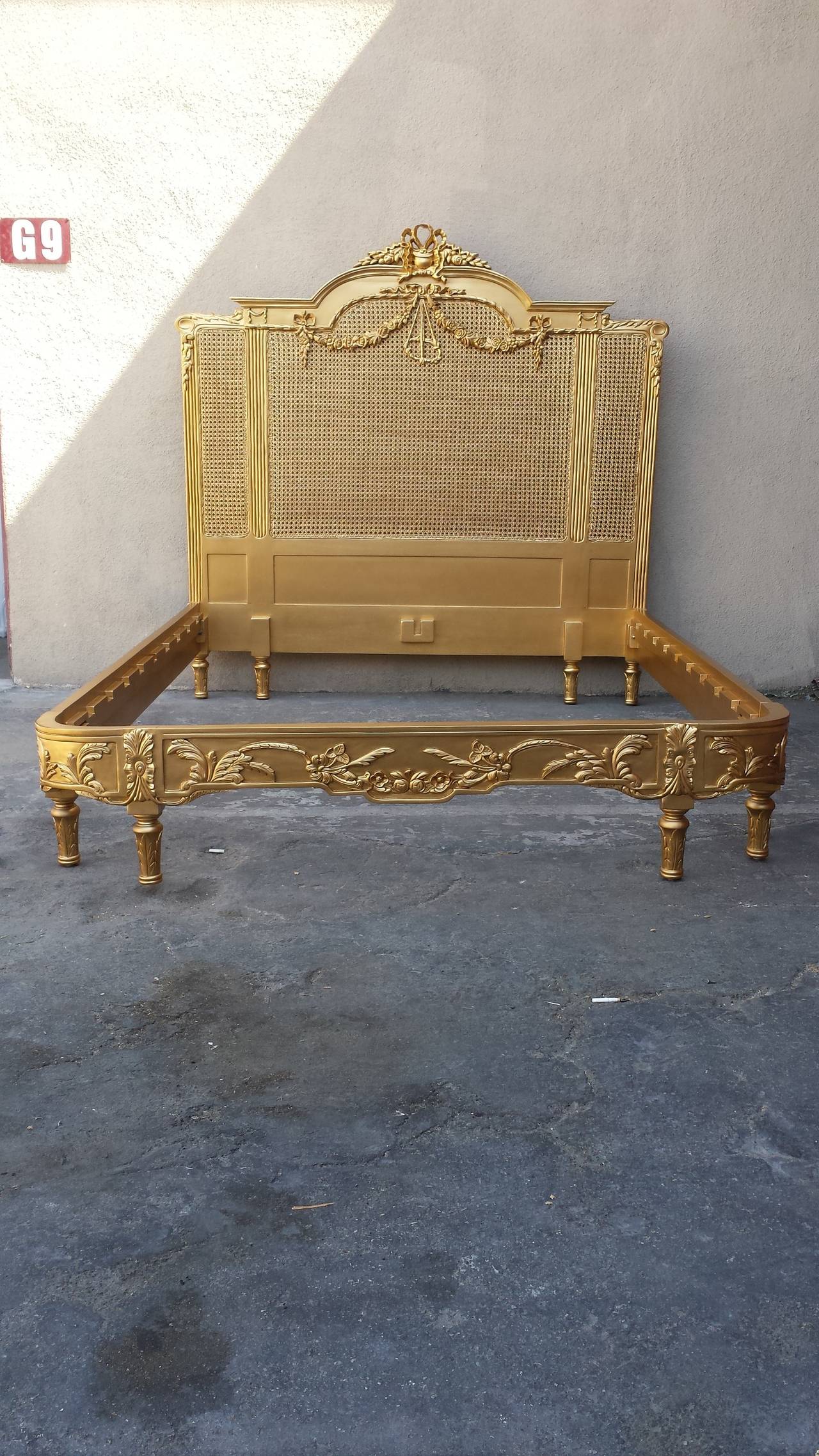 French Louis XV style bed hand carved from Mahogany wood and finished in gold. Double side cane on the headboard. This bed will accommodate any standard Queen size mattress. The bed comes with slats across and center support rail, not shown.
