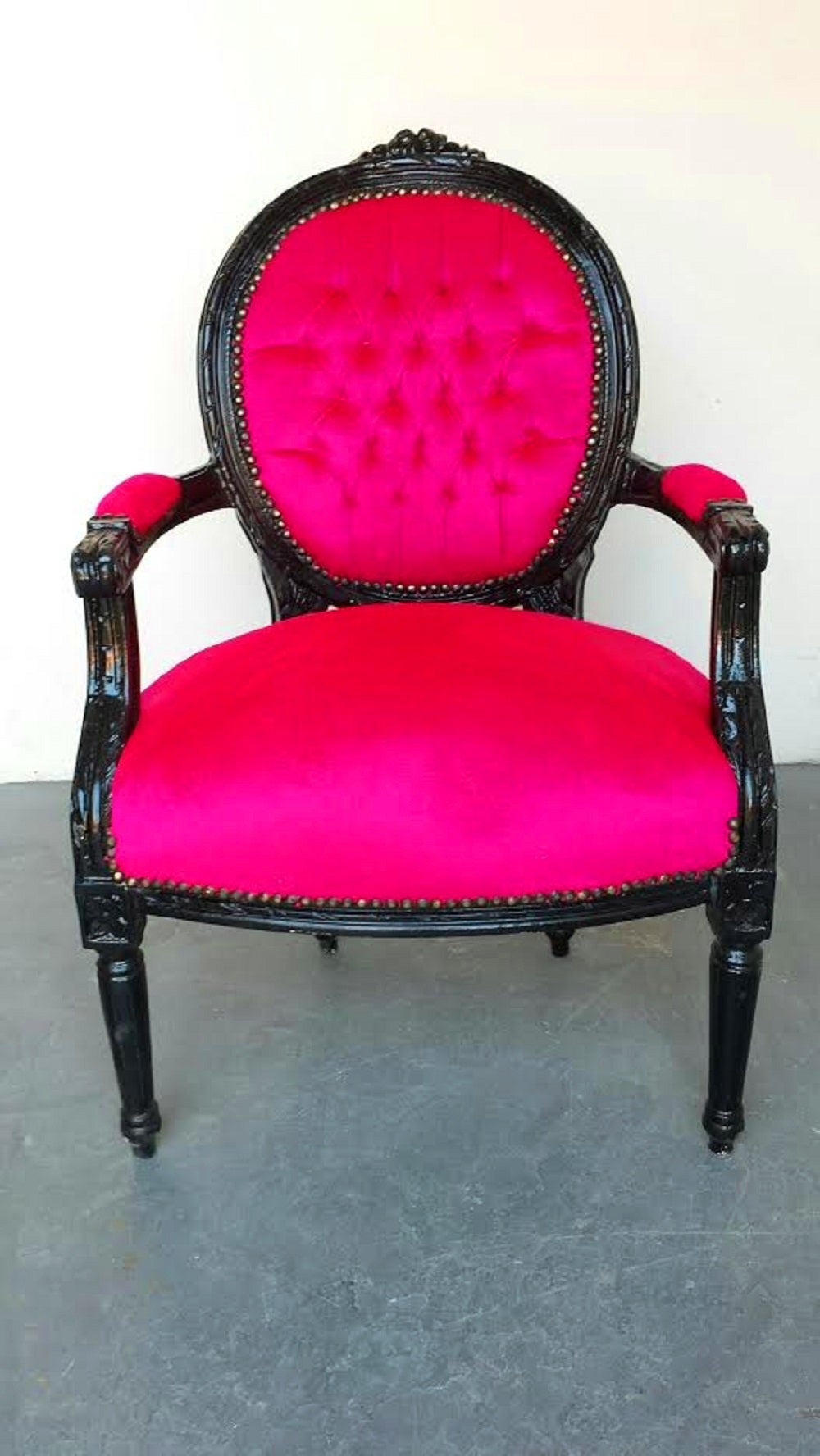 A beautiful French Louis XVI style armchair. The chair is newly painted in black and newly covered in hot pink velvet cotton fabric. Deep tufted on the back. Nailheads shown.