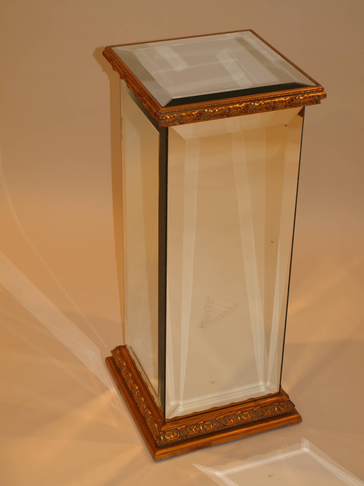 Mirrored pedestal in the mid century style. Beveled glass sits on wooden gold finish.
