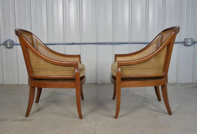 A pair of caned spoon backed slipper chairs by Baker.  Solid wood frames.  Mohair upholstered seat cushions.  These are very comfortable chairs.  Both are labeled.